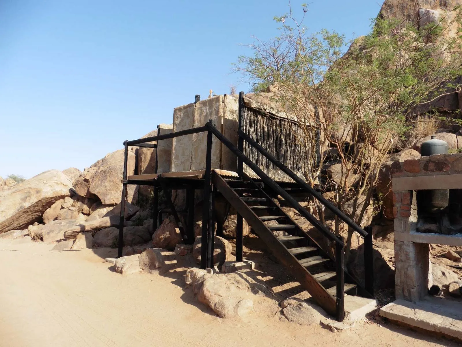 Elevated structure with stairs in a rocky desert landscape with sparse vegetation