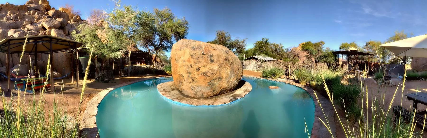 A large rock in a swimming pool in a desertlike outdoor setting