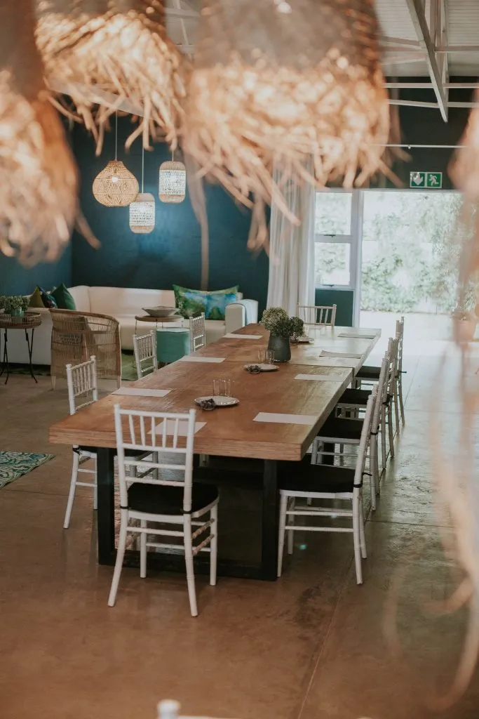 Wooden table with white chairs in a bright modern room with hanging lamps