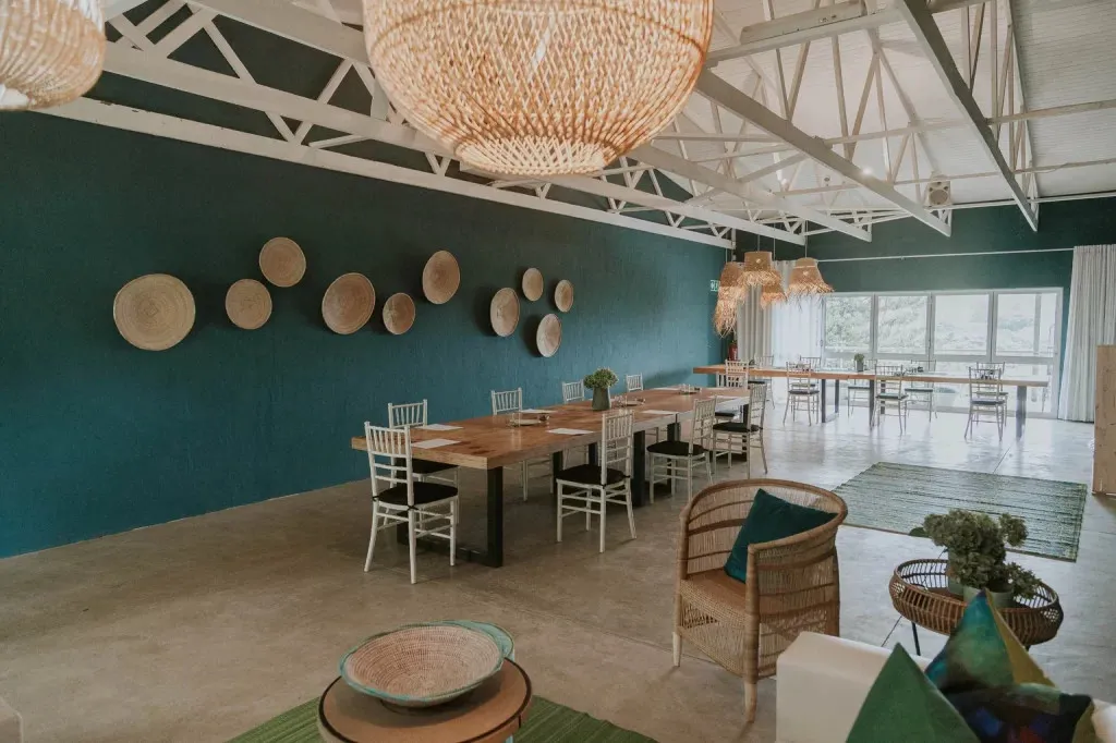 Modern dining area with wooden table chairs and woven decor on teal walls