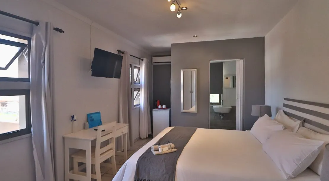 Modern hotel room with bed desk TV and ensuite bathroom