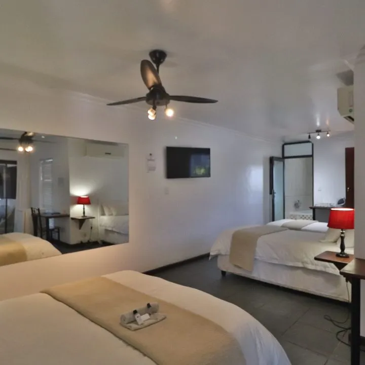Hotel room with two beds a ceiling fan and a wallmounted TV