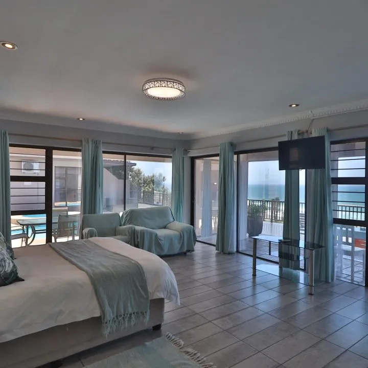 Modern bedroom with large windows ocean view and a TV