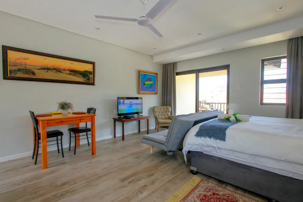 Modern bedroom with a bed desk TV and balcony access