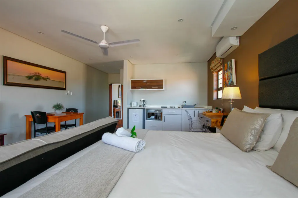 Cozy bedroom with kitchenette ceiling fan and artwork on the wall