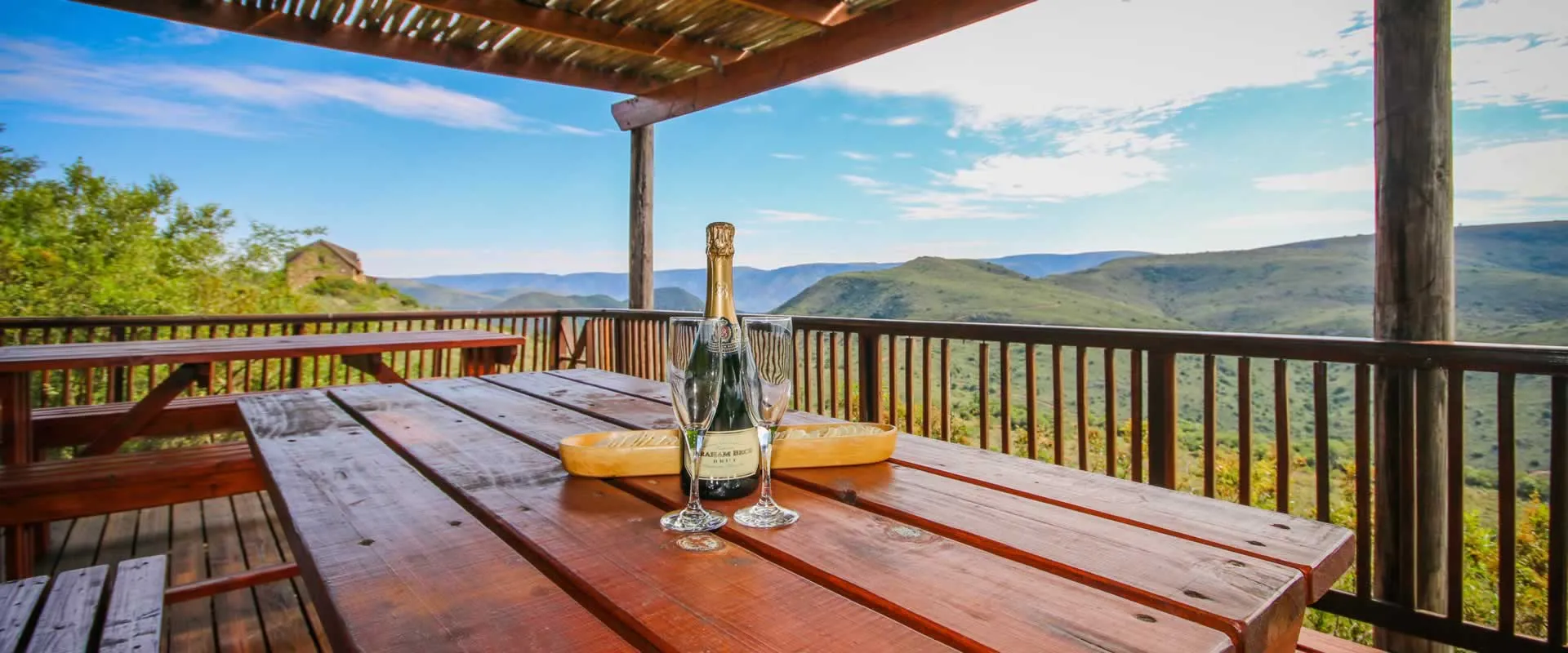 Wooden table with wine bottle and glasses overlooking a scenic valley