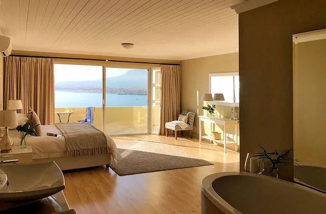 Bedroom with lake view large windows wooden floor and adjacent bathroom