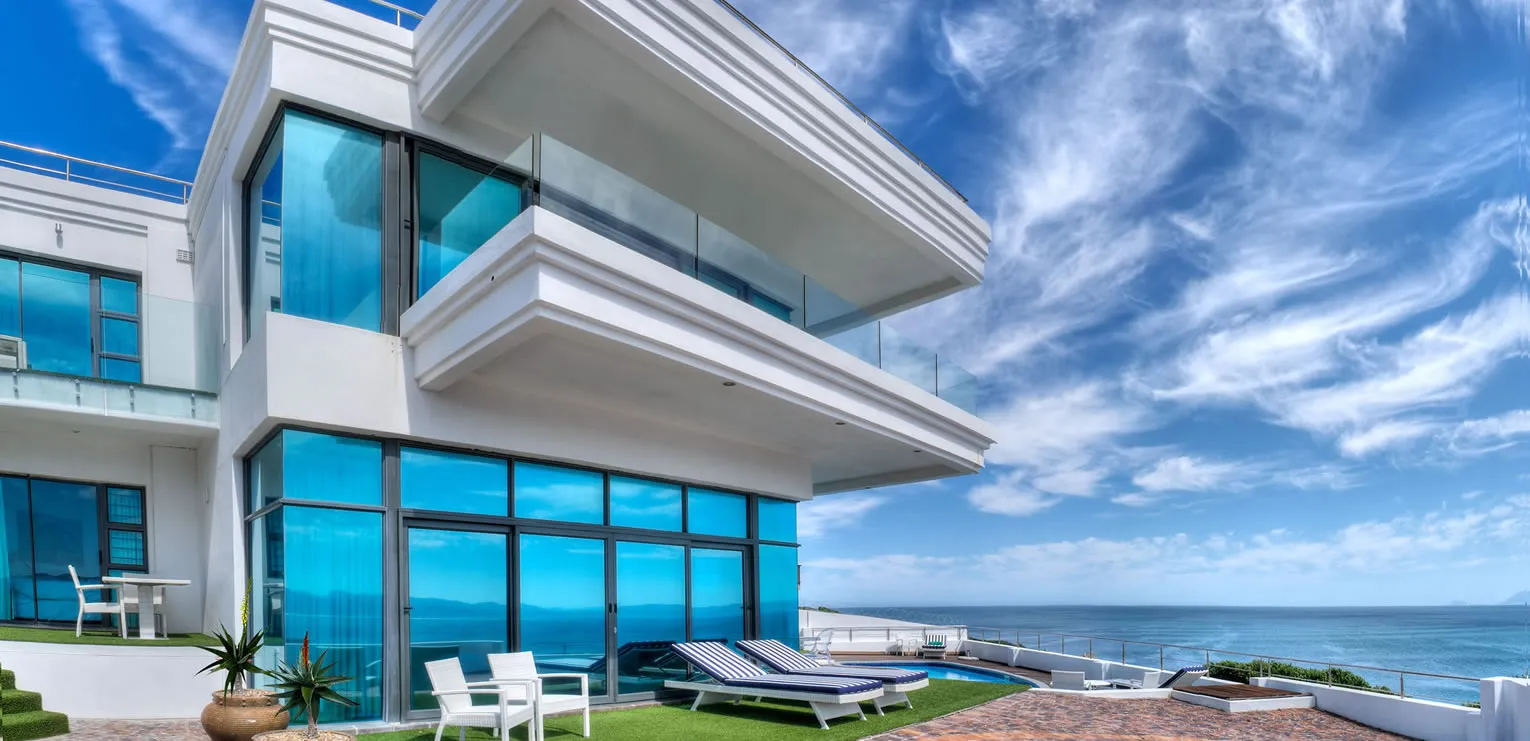 Modern beachfront house with large windows outdoor seating and ocean view