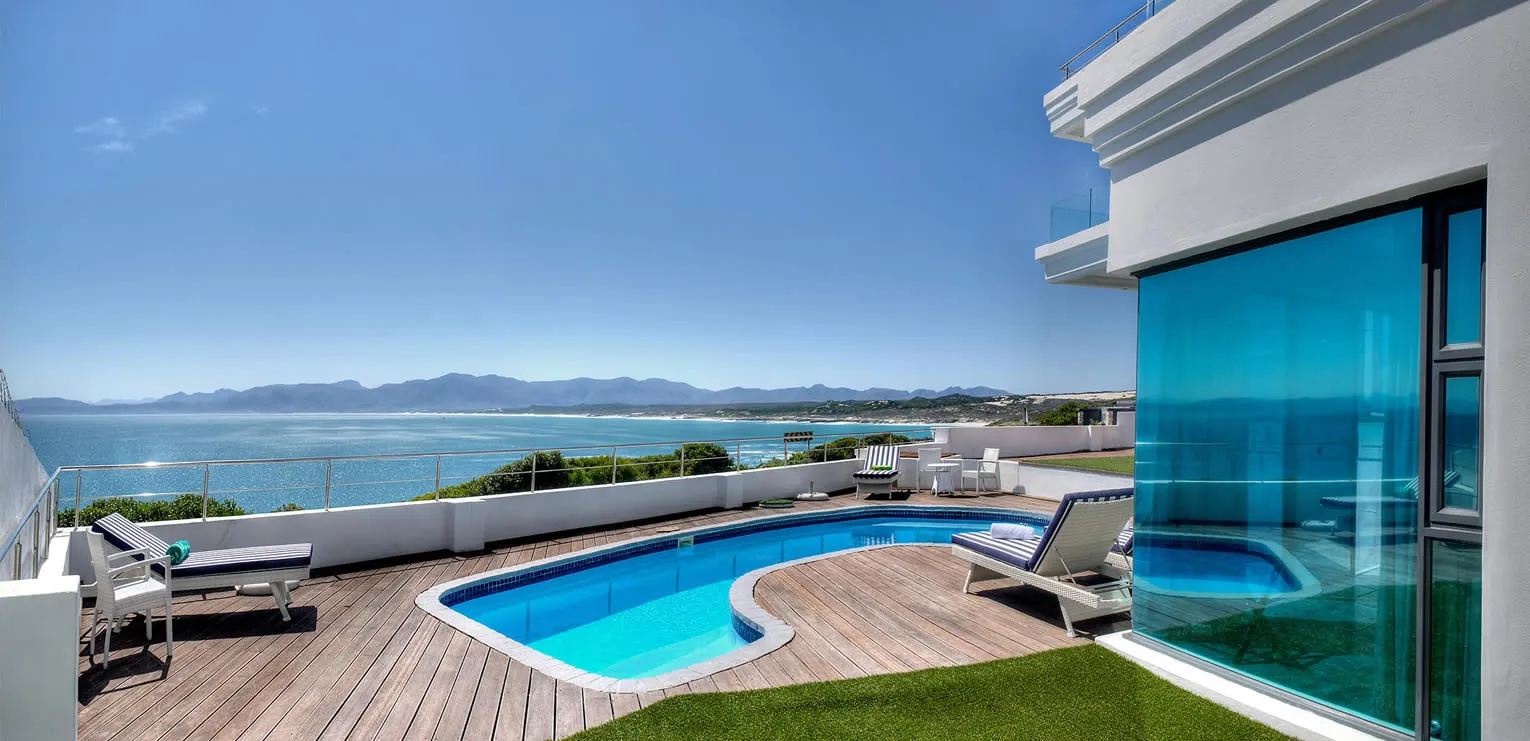 Modern rooftop pool with ocean view lounge chairs and clear blue sky