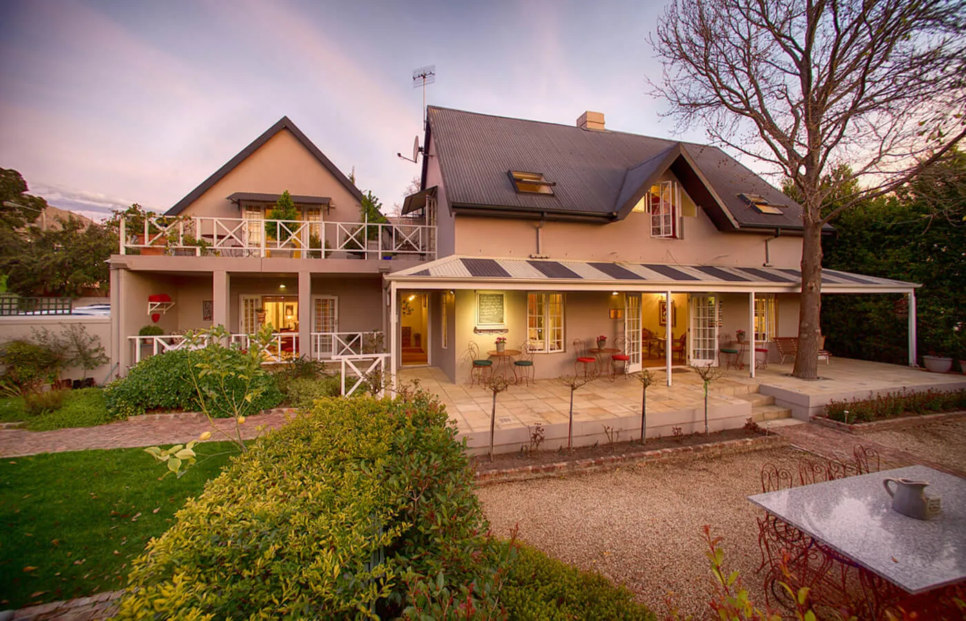 Large twostory house with garden and patio furniture at sunset
