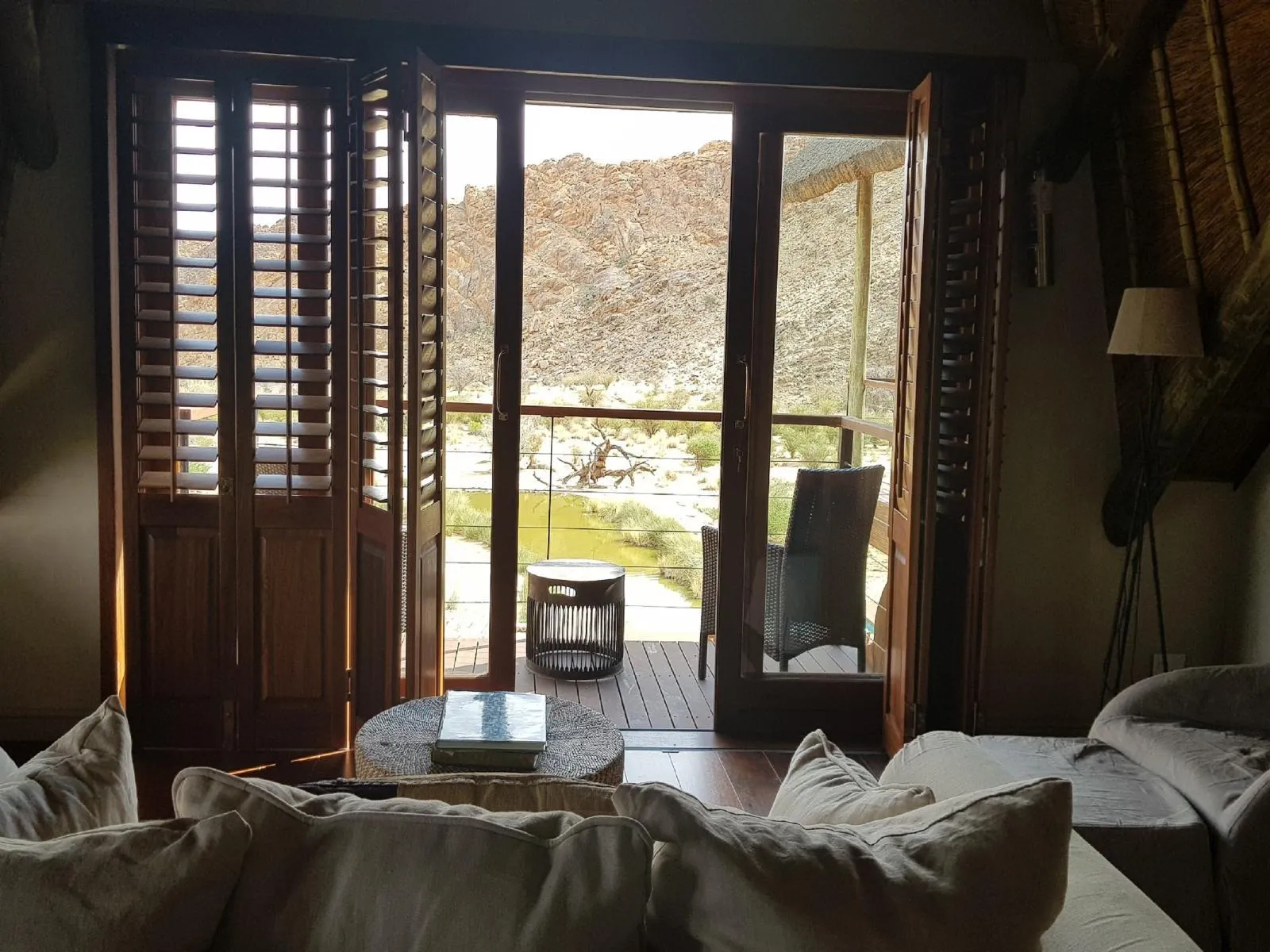 Open wooden doors to a balcony with a view of a dry landscape