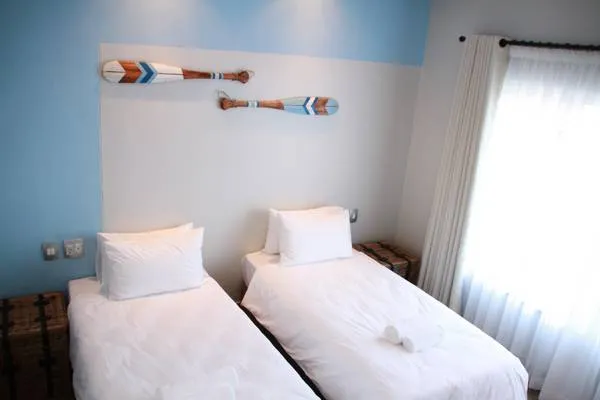 Two single beds in a bright room with oars on the wall and window