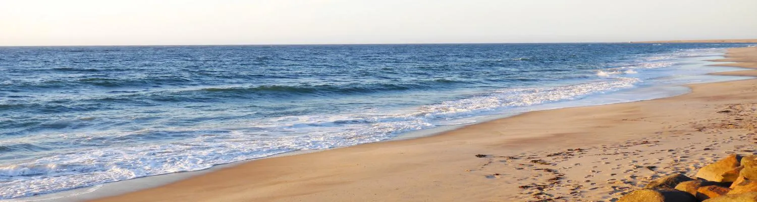 Sandy beach with gentle waves rolling onto the shore under a clear sky
