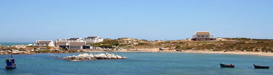 Coastal scene with buildings boats on calm water and sandy shore