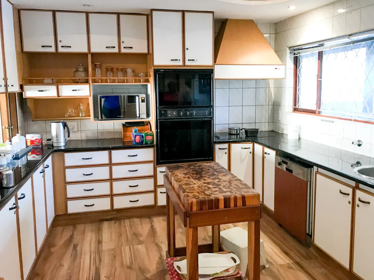 Modern kitchen with wooden island black appliances and large windows