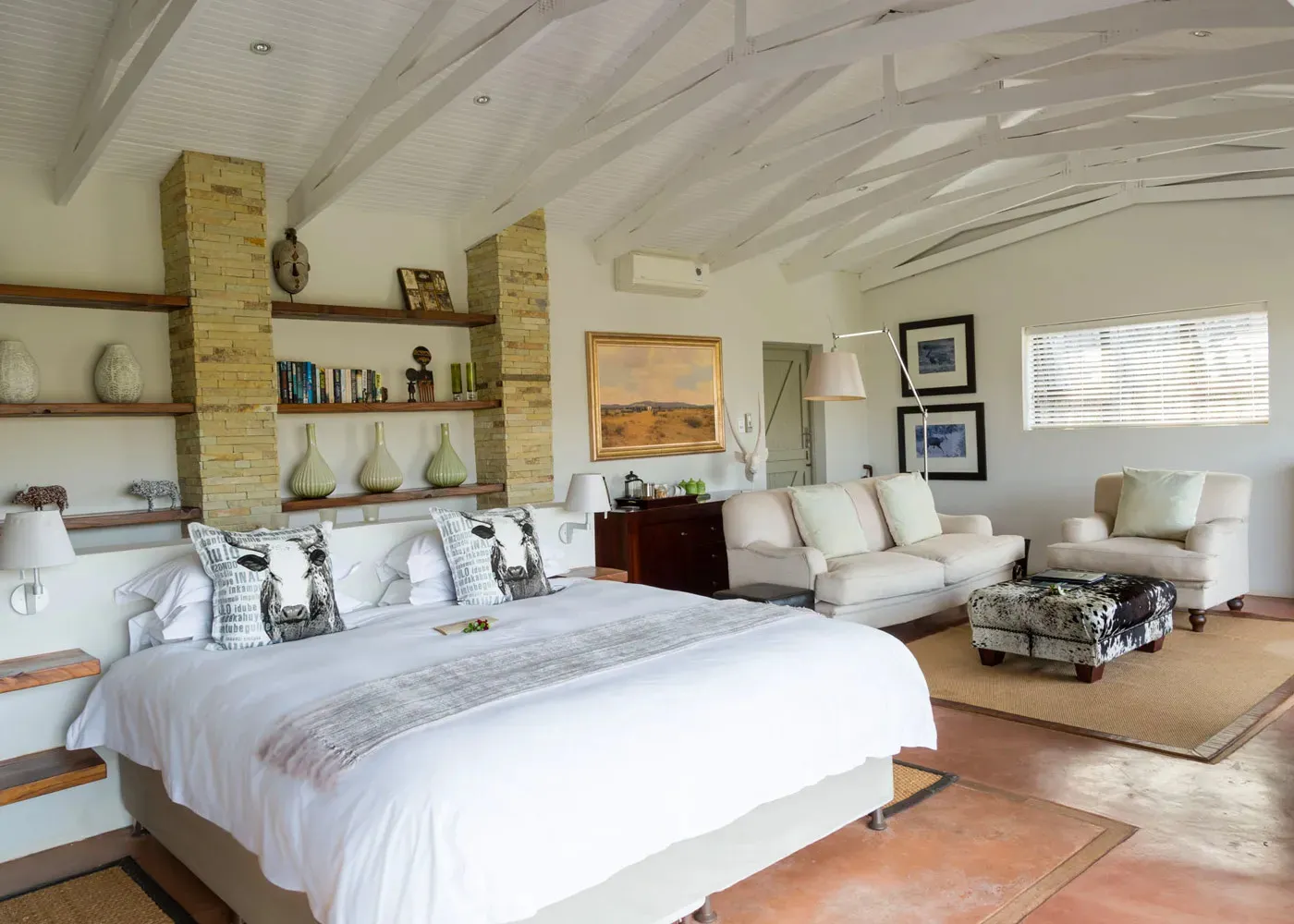 Bright bedroom with large bed sofa and decorative items on shelves and walls