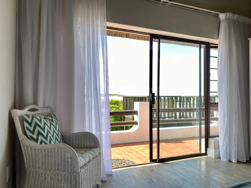 Wicker chair with pillow by sliding glass door with balcony view