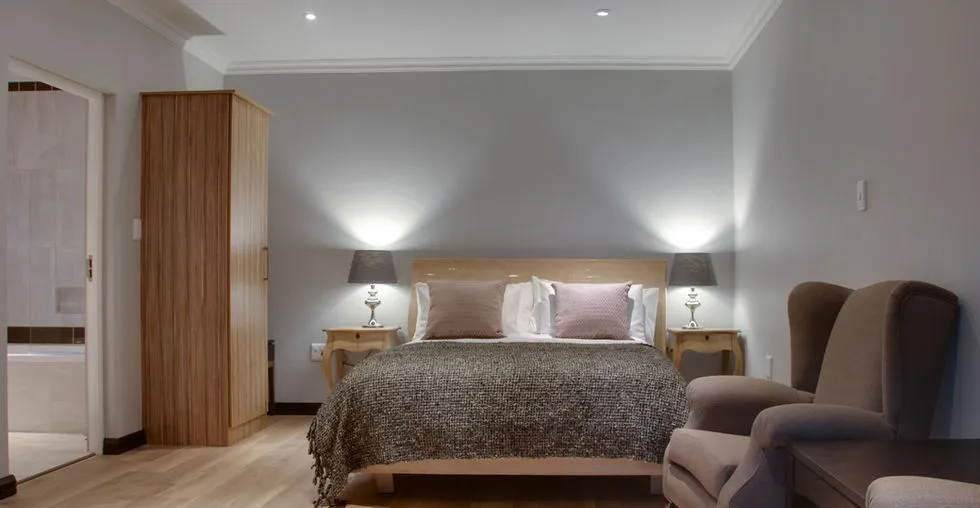 Cozy bedroom with a double bed two armchairs and bedside lamps