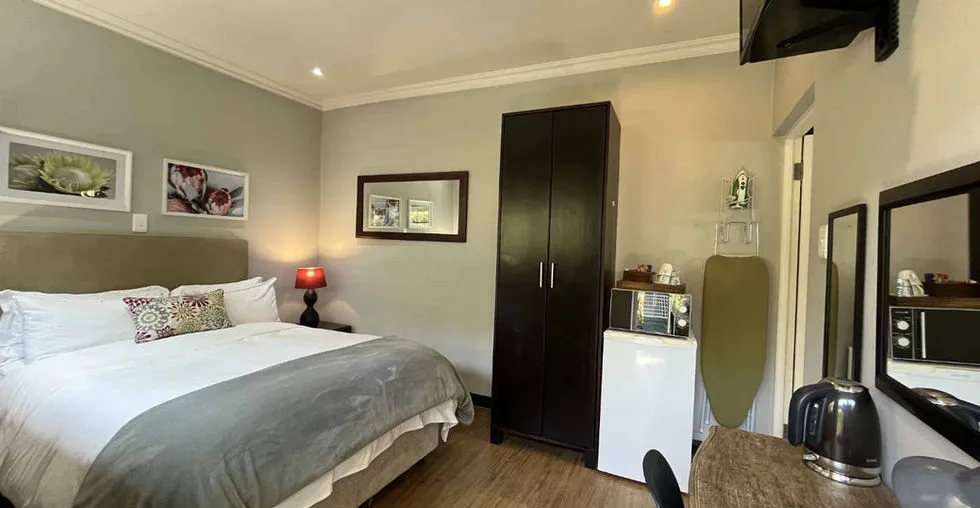 Cozy bedroom with a bed wardrobe fridge microwave and desk with a kettle