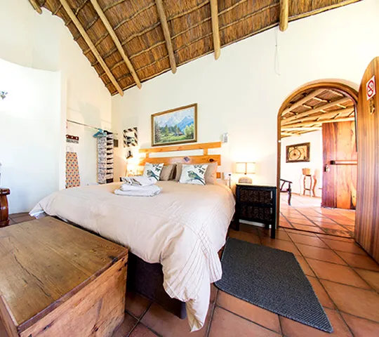 Cozy bedroom with a large bed wooden ceiling and arched doorway to another room