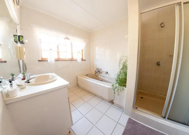 Bright bathroom with sink bathtub shower and large window