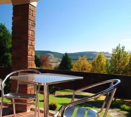 Metal table and chairs on a patio with a scenic countryside view