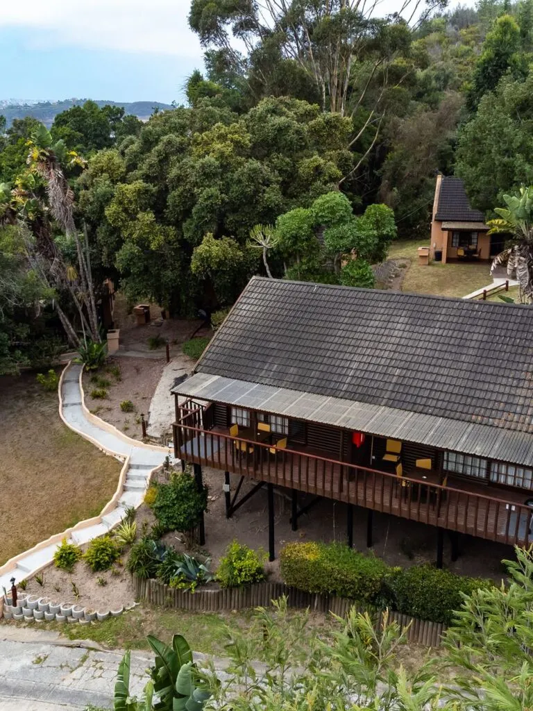 Wooden cabin on stilts in a lush forested area with a winding path