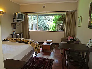 Cozy bedroom with a bed TV and large window overlooking a garden
