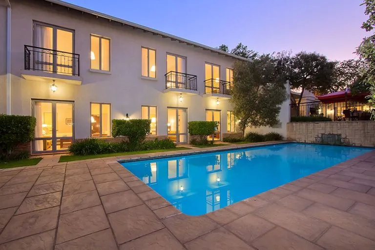 Modern house with lit windows and a swimming pool at dusk