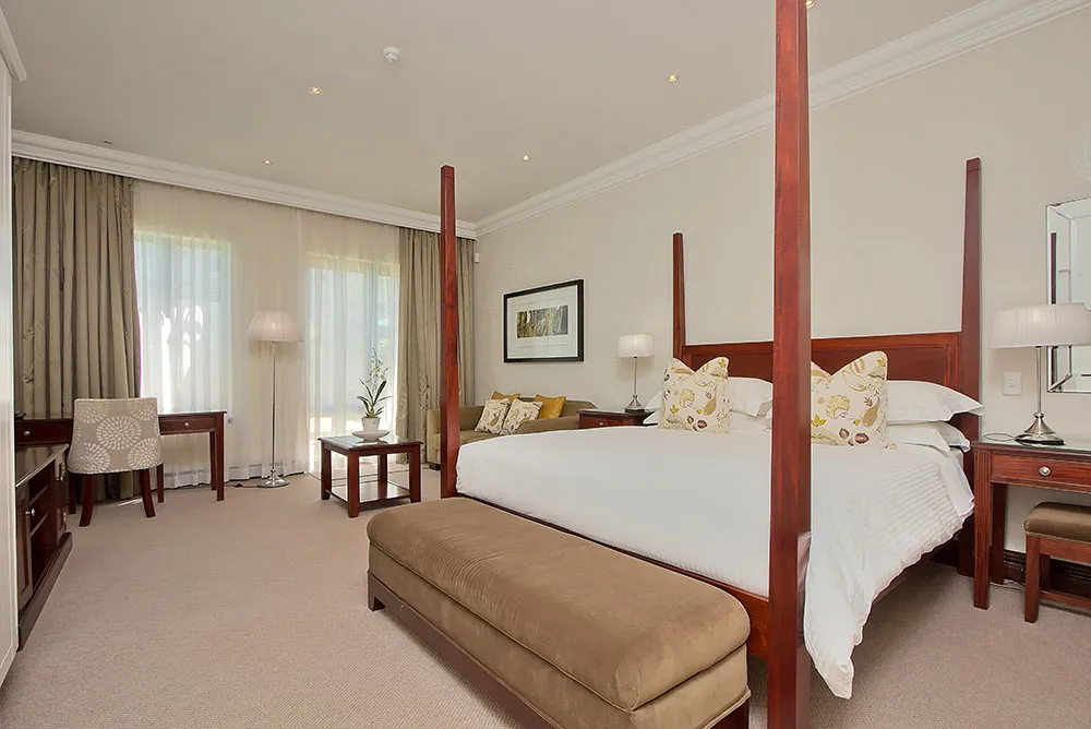 Elegant hotel room with a large bed sofa and desk near windows
