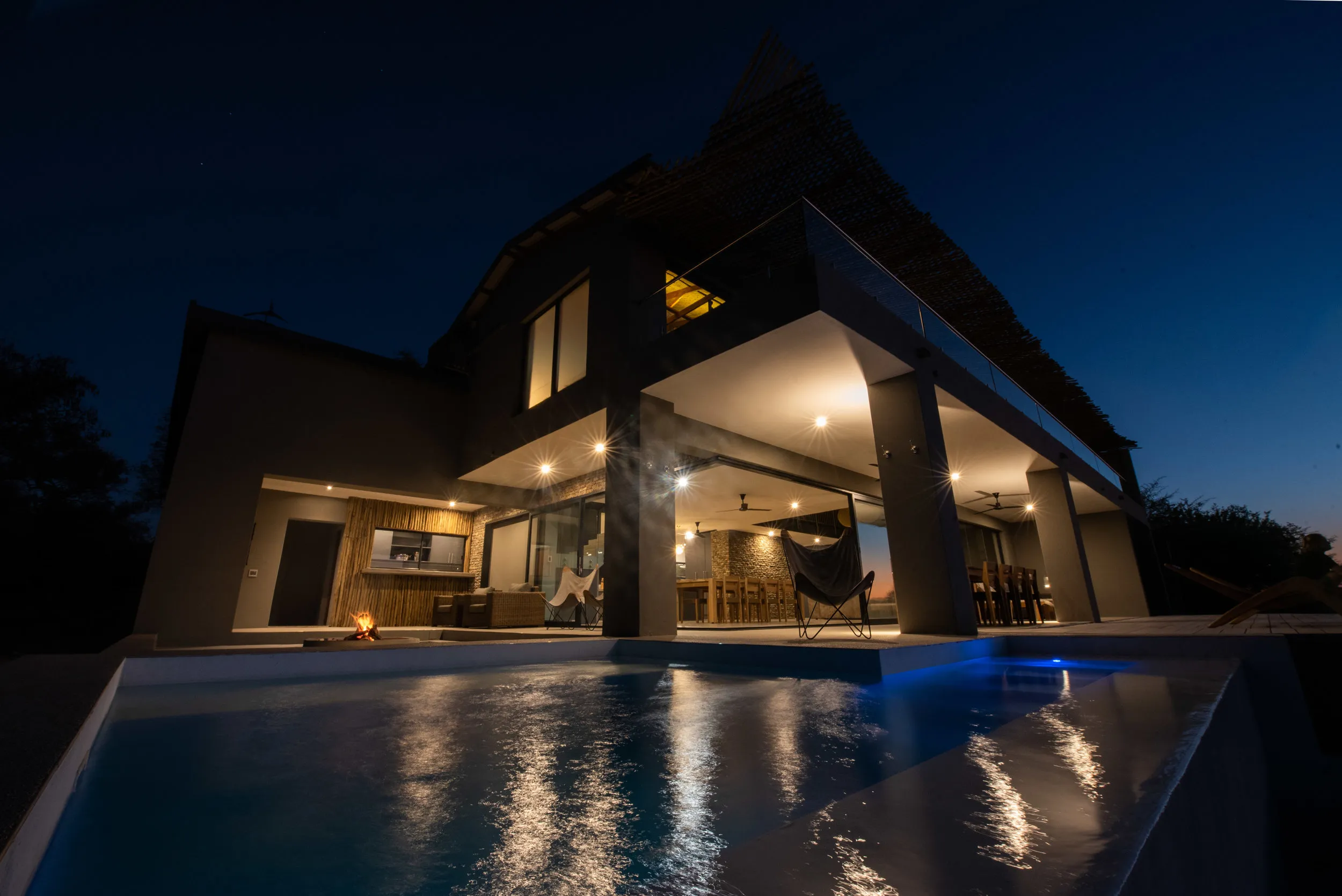 Modern house at night with lit pool and outdoor seating area