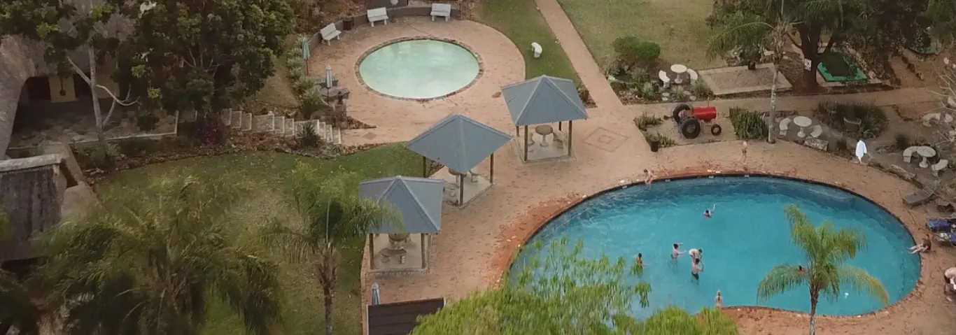 Aerial view of a resort with pools palm trees and people swimming