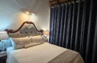 Bed with white linens in a room with dark curtains and soft lighting