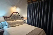 Bedroom with a large bed dark curtains and bedside lamps