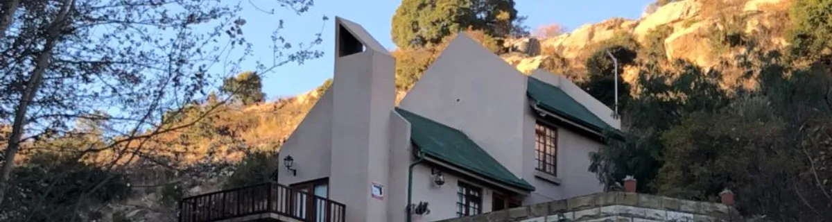 House with green roof and chimney on a hillside with trees