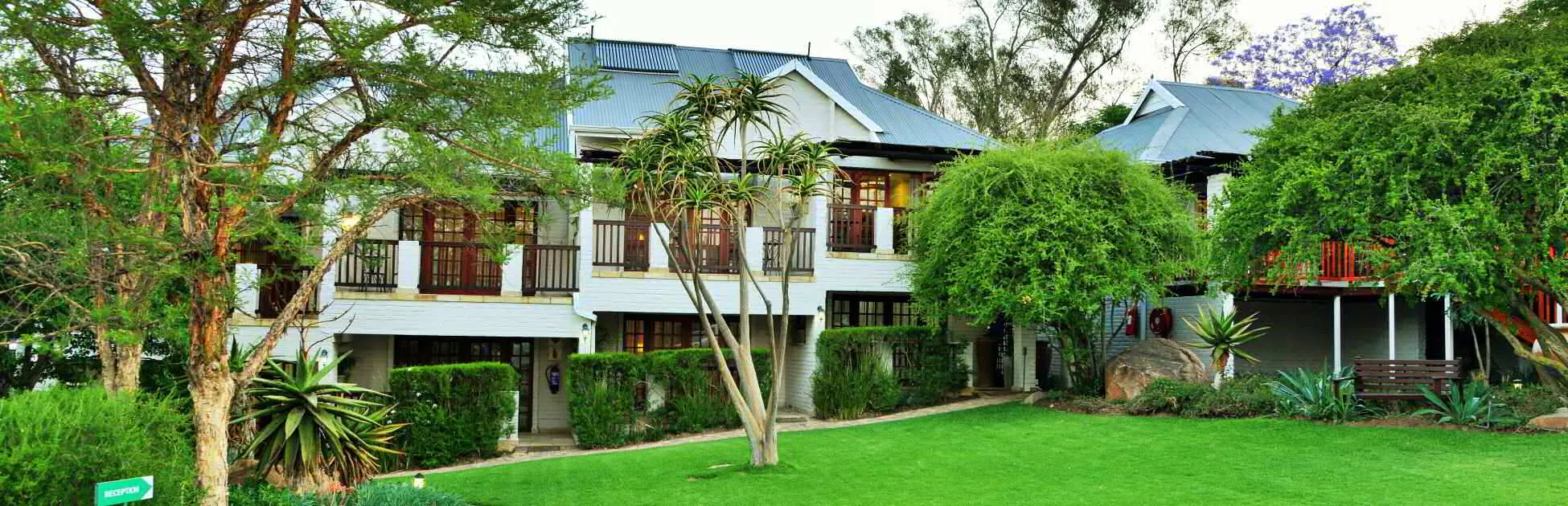 Twostory building with balconies surrounded by trees and green lawn
