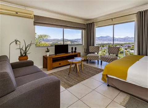 Modern living room with sofa chairs TV and large windows overlooking mountains