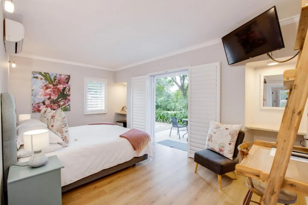 Bedroom with bed TV armchair and open door to outdoor patio