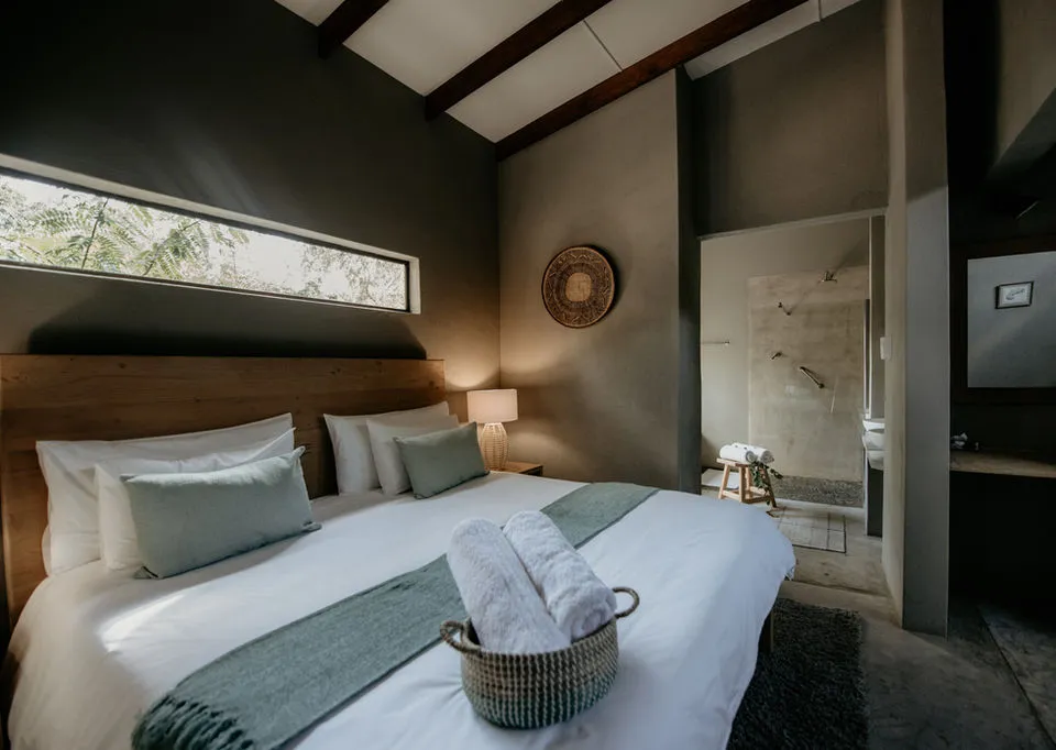 Modern bedroom with large bed towels and ensuite bathroom visible