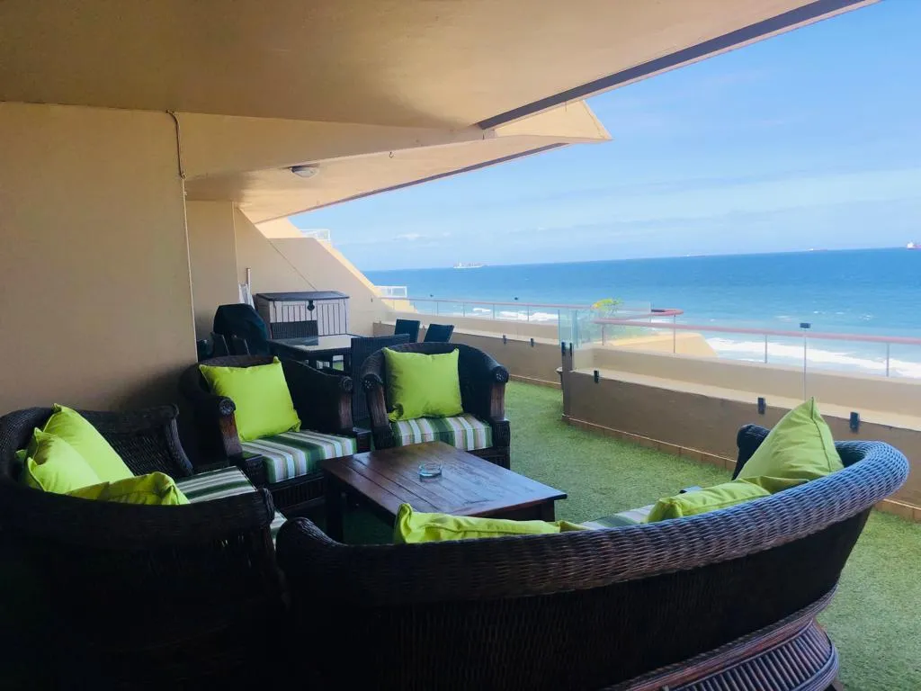 Outdoor patio with wicker furniture green cushions and ocean view