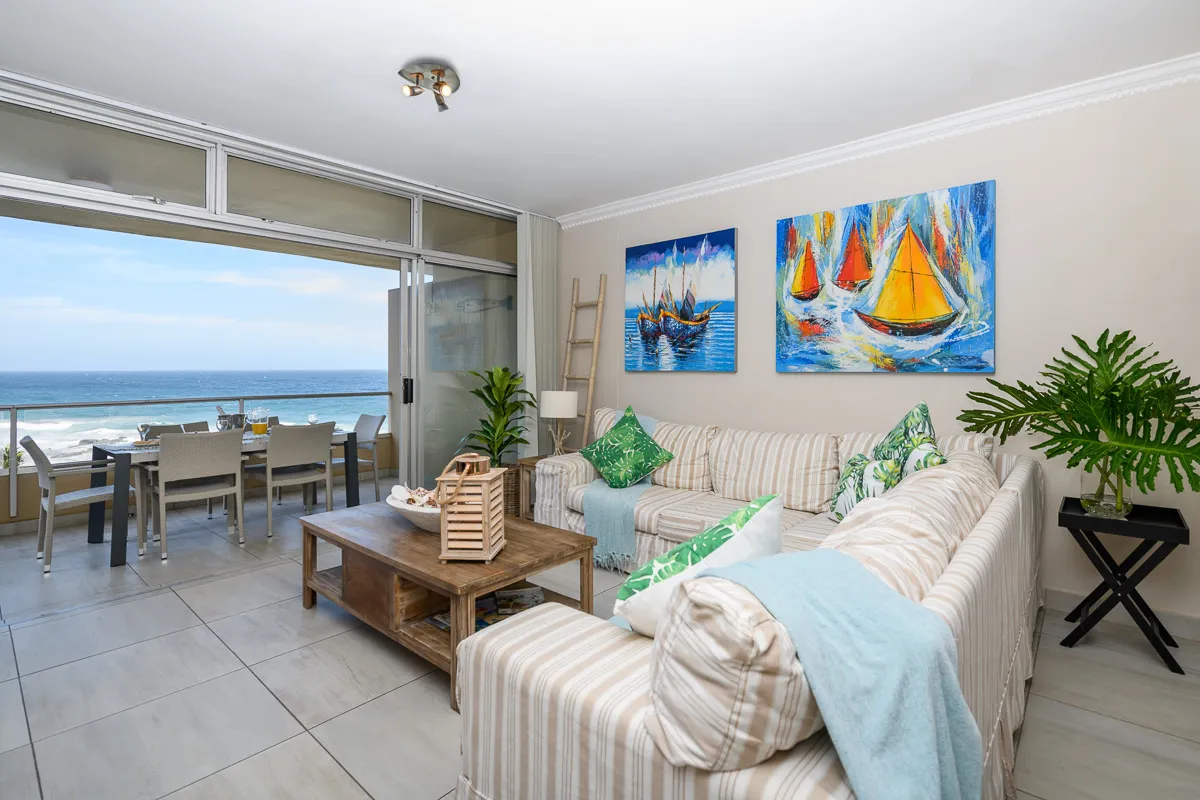 Living room with ocean view striped sofa and sailboat paintings on the wall