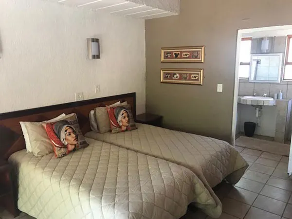 Two single beds in a small bedroom with an adjacent bathroom