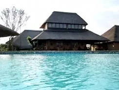 Thatchedroof building with pool in front trees in background