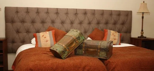 Two old chests on a bed with orange and brown bedding in a bedroom