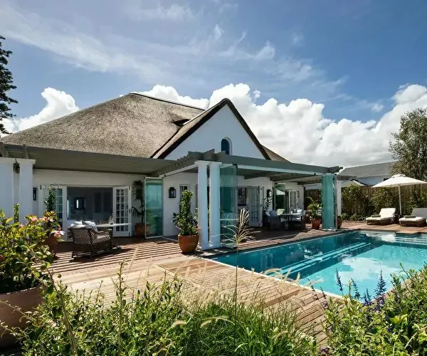 Modern house with a thatched roof pool and outdoor seating area
