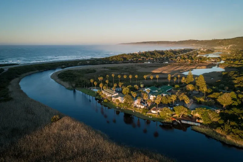 Aerial view of a river flowing into the ocean with buildings and palm trees