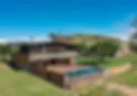 Modern house with pool in lush green landscape under blue sky