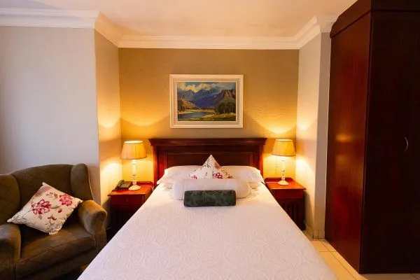Cozy bedroom with a double bed side tables lamps and a painting