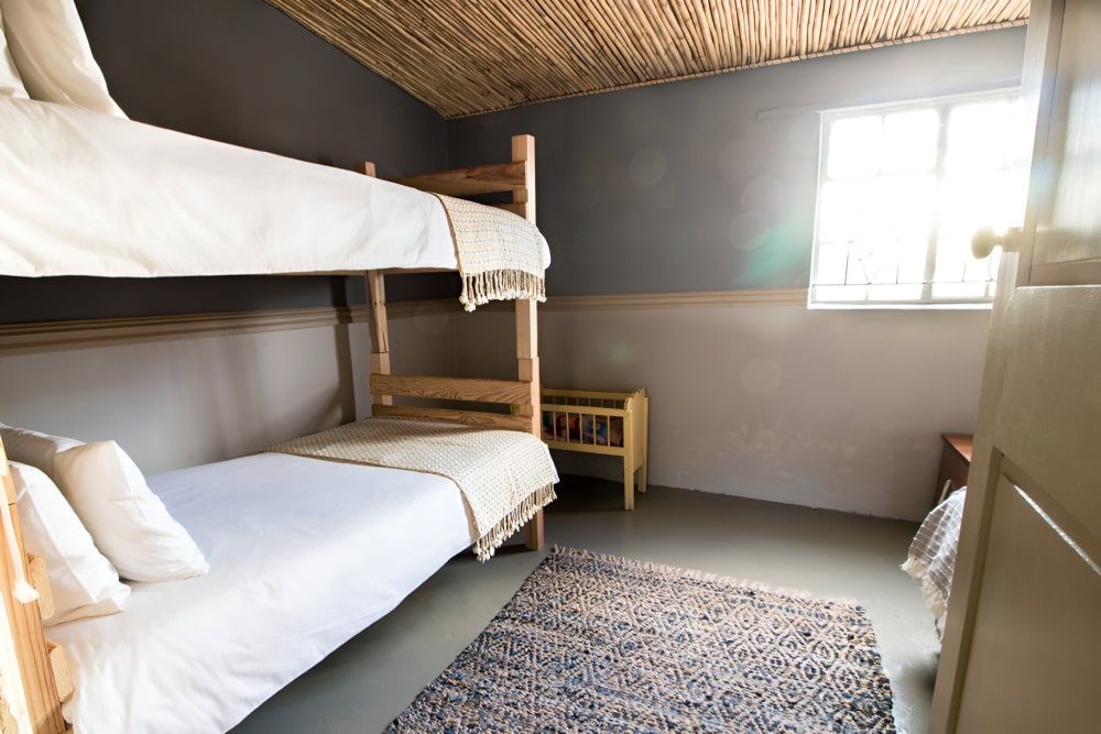 Cozy bedroom with wooden bunk beds, woven rug, and open door.