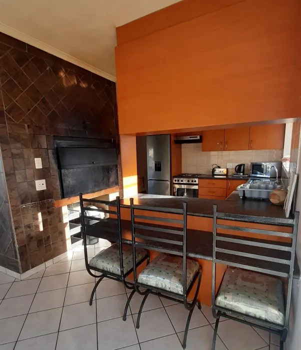 Kitchen with orange cabinets black chairs and tiled floor